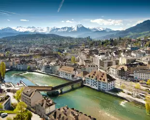 Lucerne ariel city view under warm-looking sunshine and a background of mountain peaks.